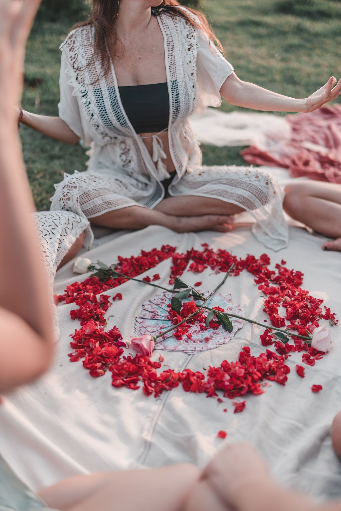Group of female friends having fun making love spell rituals with rose petals and tarot cards