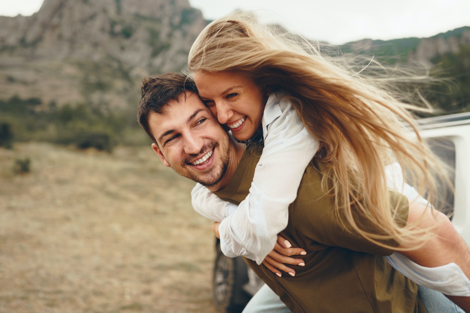 Happy loving couple hiking and hugging in mountains