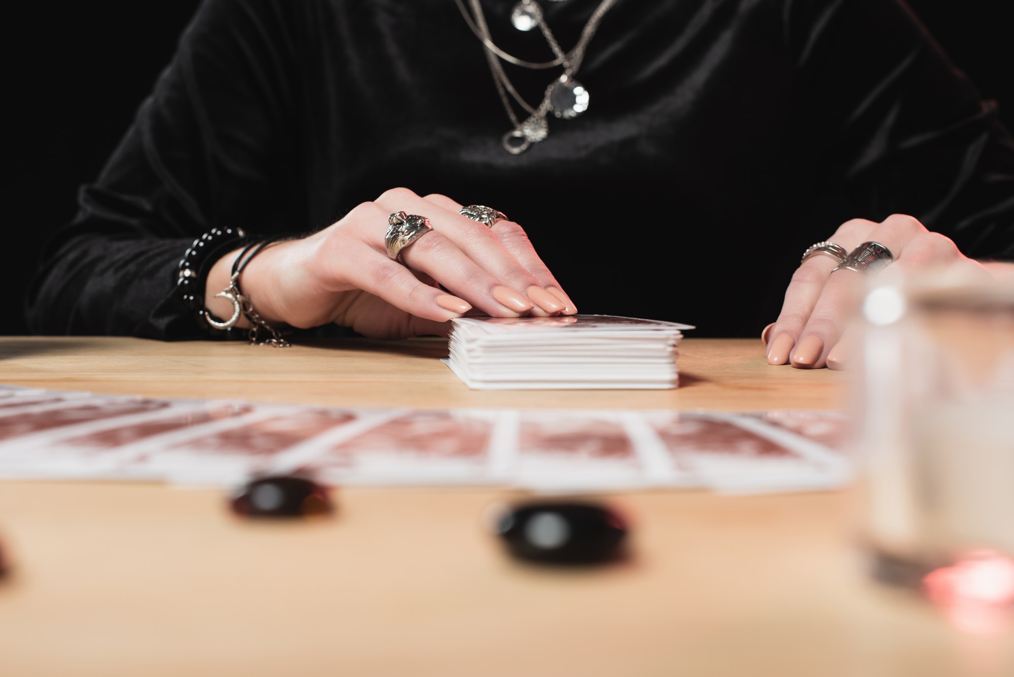 selective focus of female psychic laying tarot cards near divination stones