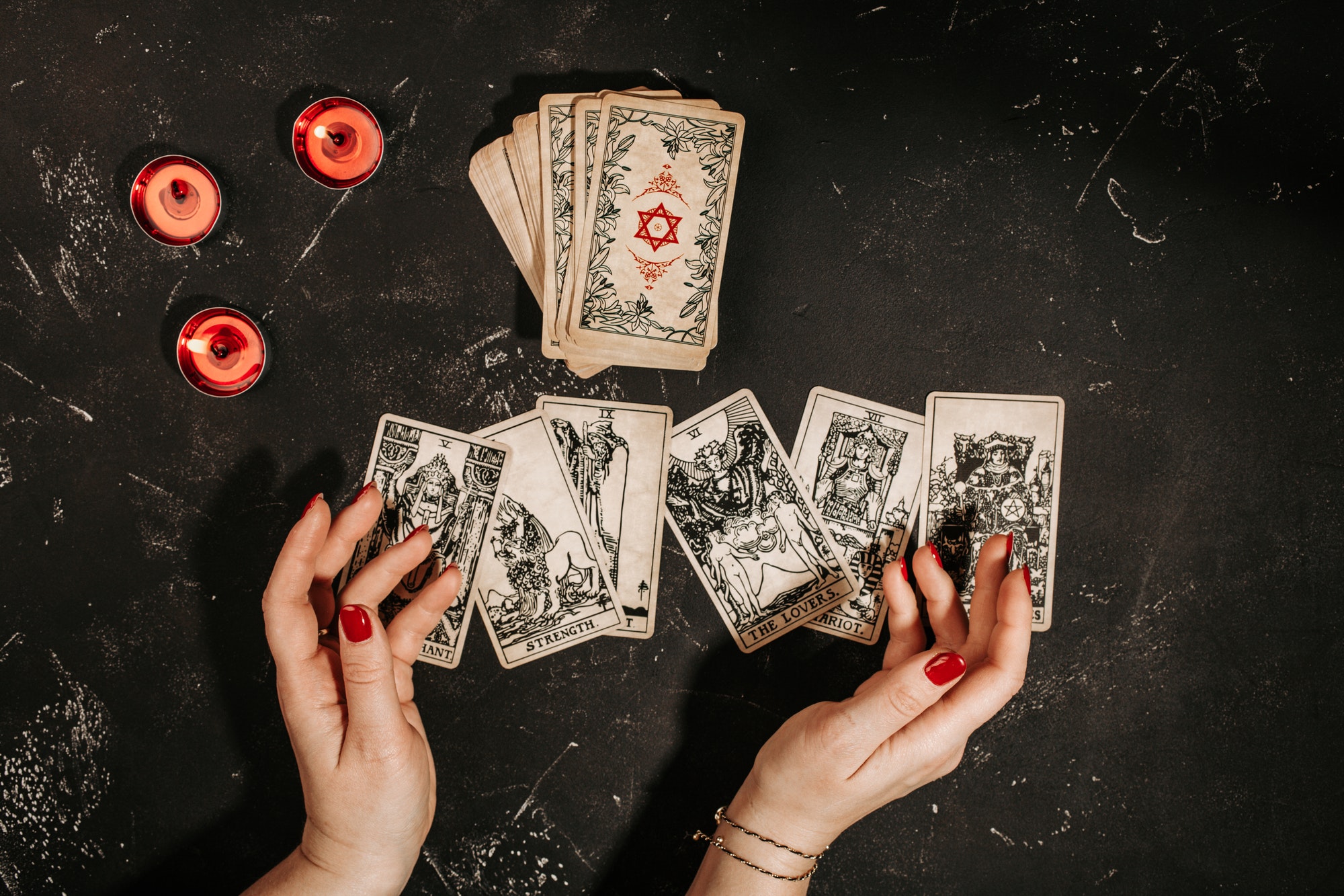 Tarot cards and female hands of fortune teller on black magic table